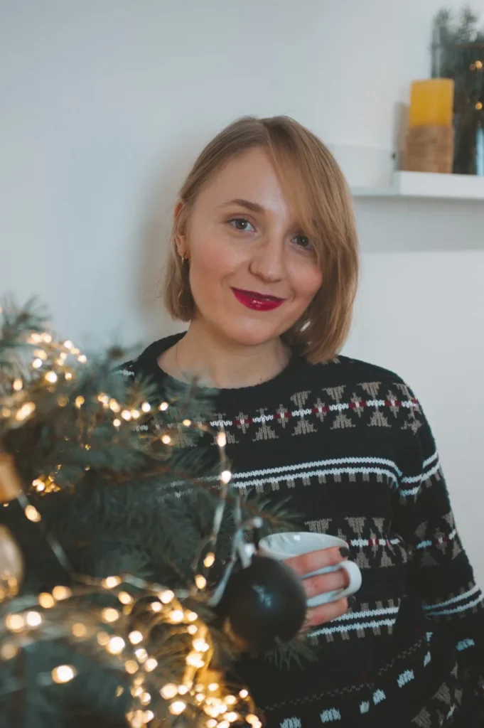 Christmas hoodie outfit ideas with a cozy holiday layer beside a decorated tree