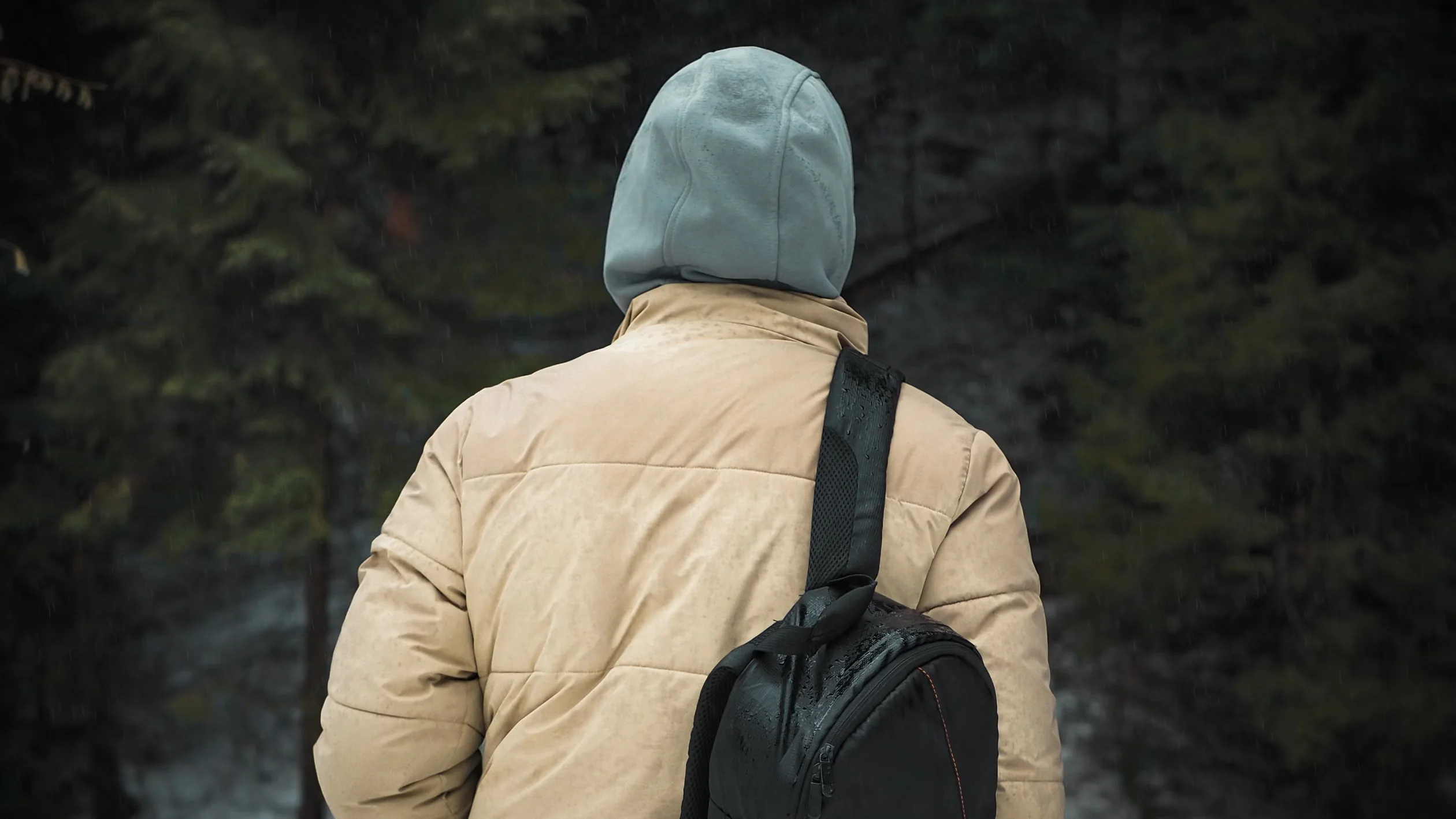 Funny camping gifts illustrated by a camper in a hoodie on a rainy forest trail
