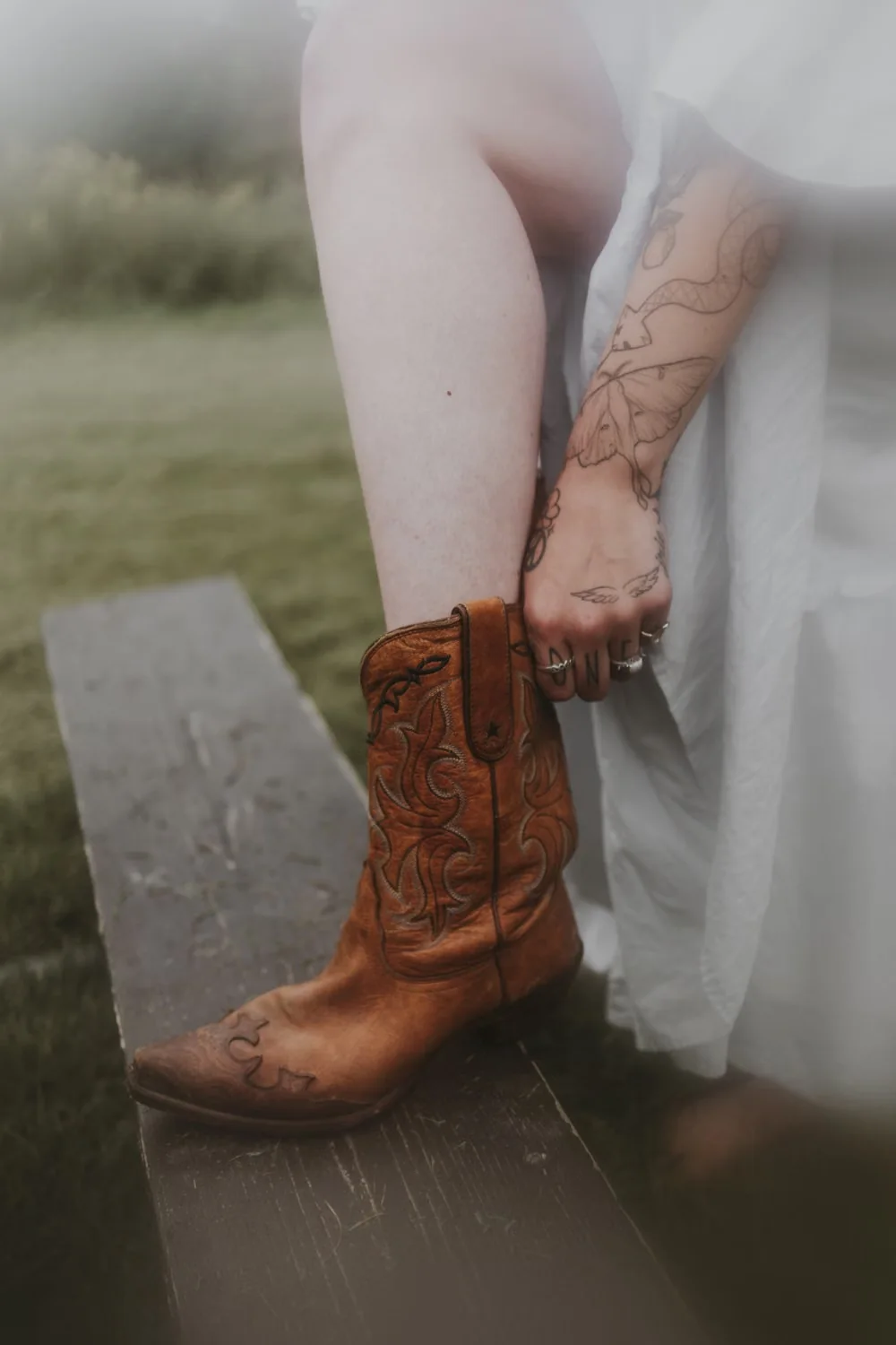 Western hoodie outfit ideas featuring brown leather cowboy boots outdoors