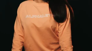 Woman wearing an orange sweatshirt and jeans as oversized graphic sweatshirt styling inspiration