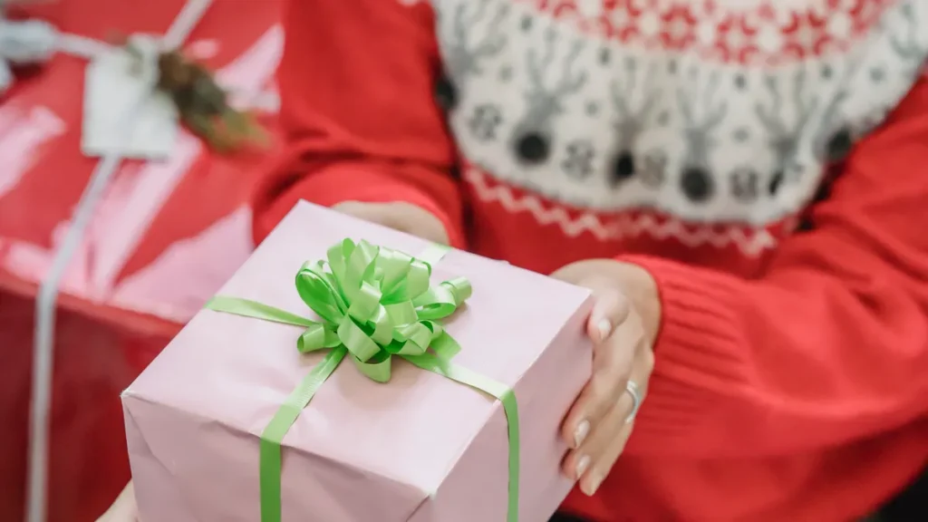 Friends exchanging a wrapped Christmas present at a holiday gathering