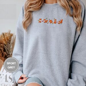 Person wearing a sport grey Autumn Foxes Embroidered Sweatshirt