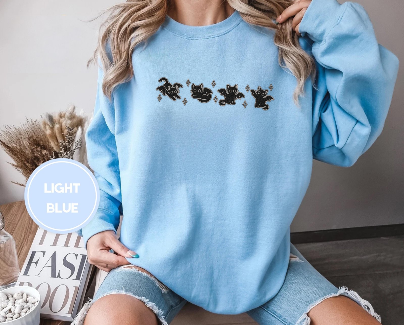 Person wearing a light blue Bat Wing Cats Embroidered Sweatshirt
