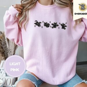 Person wearing a light pink Bat Wing Cats Embroidered Sweatshirt