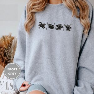 Person wearing a sport grey Bat Wing Cats Embroidered Sweatshirt