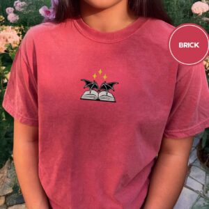 Person wearing a brick Bat Wings and Book Embroidered T-Shirt