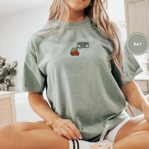 Person wearing a bay Beep Beep Driving Frog Embroidered T-Shirt