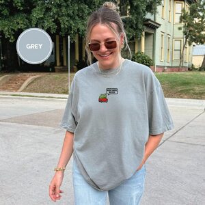 Person wearing a grey Beep Beep Driving Frog Embroidered T-Shirt