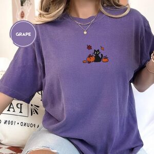 Person wearing a grape Black Cat and Pumpkins Embroidered T-Shirt