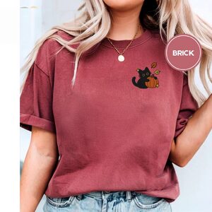 Person wearing a brick Black Cat With Autumn Leaves Embroidered T-Shirt