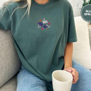 Person wearing a blue spruce Books and Flowers Embroidered T-Shirt