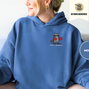 Person wearing an indigo blue Boxing Raccoon Embroidered Hoodie