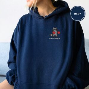 Person wearing a navy Boxing Raccoon Embroidered Hoodie