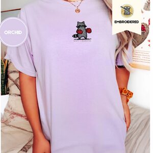 Person wearing an orchid Boxing Raccoon Why I Oughta Embroidered T-Shirt