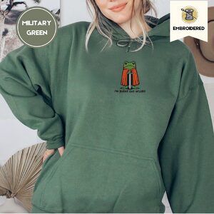 Person wearing a military green Burnt Out Frog Embroidered Hoodie