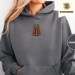 Person wearing a charcoal Burnt Out Frog Knight Embroidered Hoodie