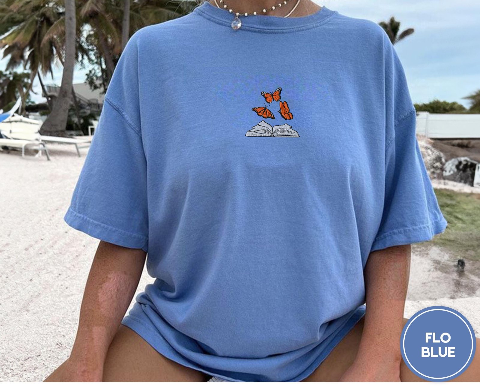 Person wearing a flo blue Butterflies and Open Book Embroidered T-Shirt