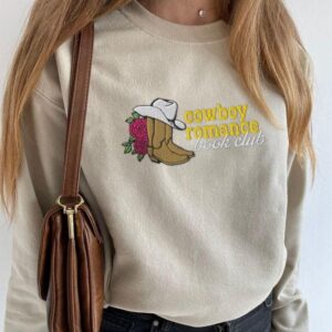 Person wearing a sand Cowboy Romance Book Club Embroidered Sweatshirt