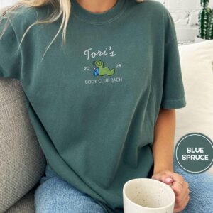 Person wearing a blue spruce Custom Bookworm Book Club Embroidered T-Shirt