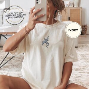Person wearing an ivory Dragon and Crescent Moon Embroidered T-Shirt
