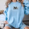 Person wearing a light blue Dragon And Daisies Book Embroidered Sweatshirt