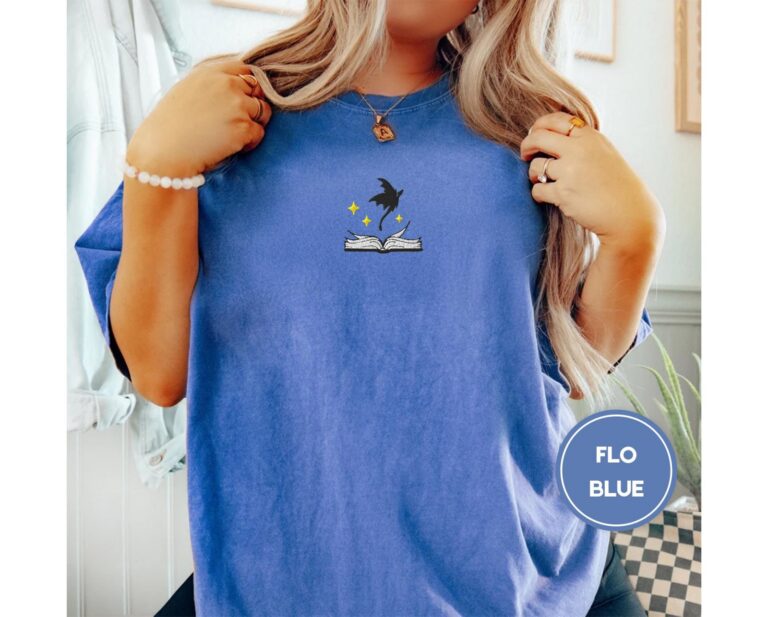 Person wearing a flo blue Dragon and Open Book Embroidered T-Shirt