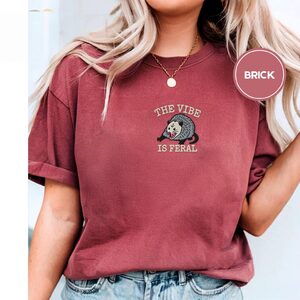 Person wearing a brick Feral Possum Embroidered T-Shirt