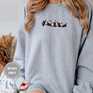 Person wearing a sport grey Five Playful Black Cats Embroidered Sweatshirt