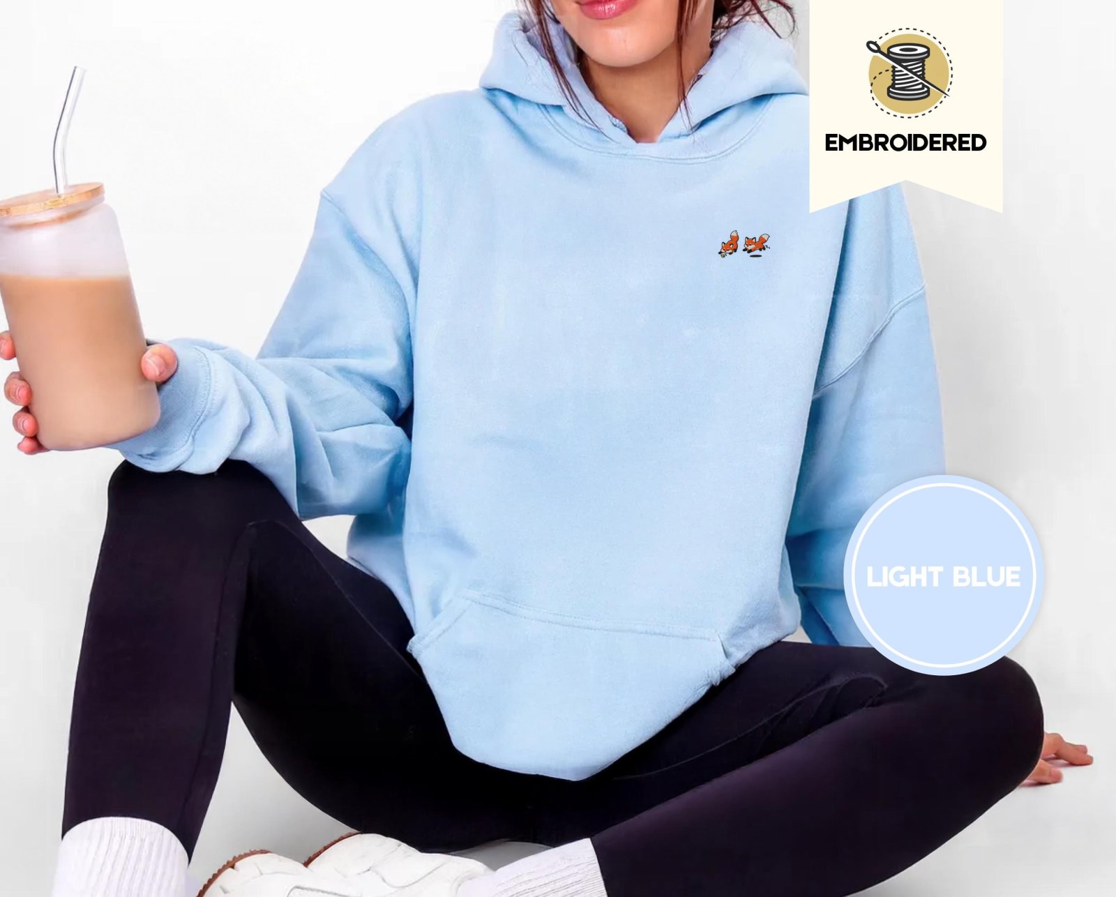 Person wearing a light blue Five Playful Foxes Embroidered Hoodie