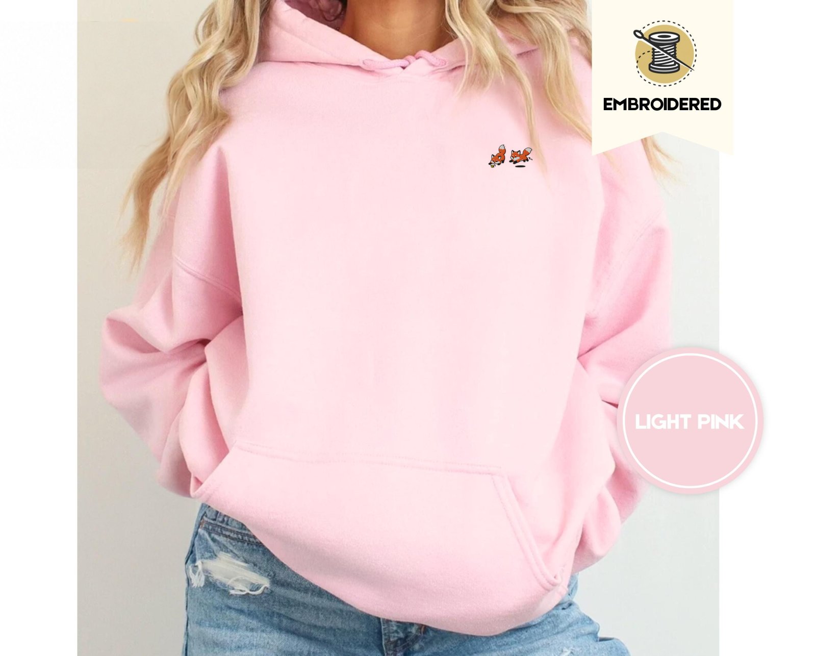Person wearing a light pink Five Playful Foxes Embroidered Hoodie