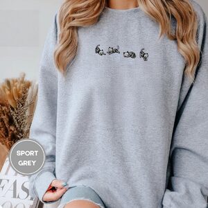 Person wearing a sport grey Five Posing Skeleton Cats Embroidered Sweatshirt