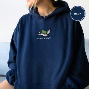 Person wearing a navy Frog Riding Goose Embroidered Hoodie