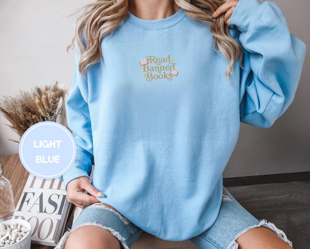 Person wearing a light blue Gold Read Banned Books Embroidered Sweatshirt