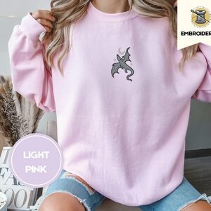 Person wearing a light pink Gray Dragon and Stars Embroidered Sweatshirt