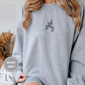Person wearing a sport grey Gray Dragon and Stars Embroidered Sweatshirt