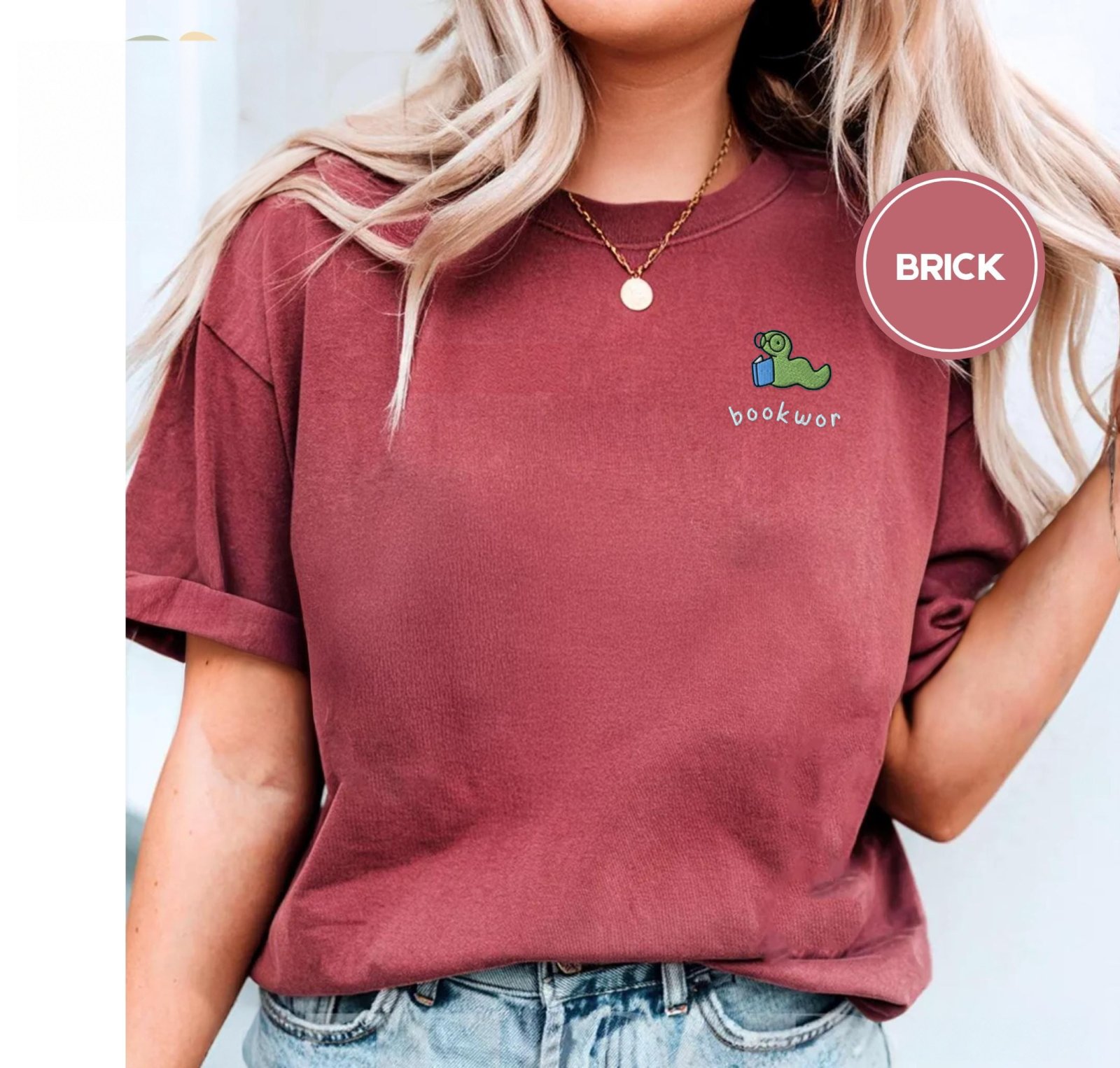 Person wearing a brick Green Bookworm Blue Book Embroidered T-Shirt