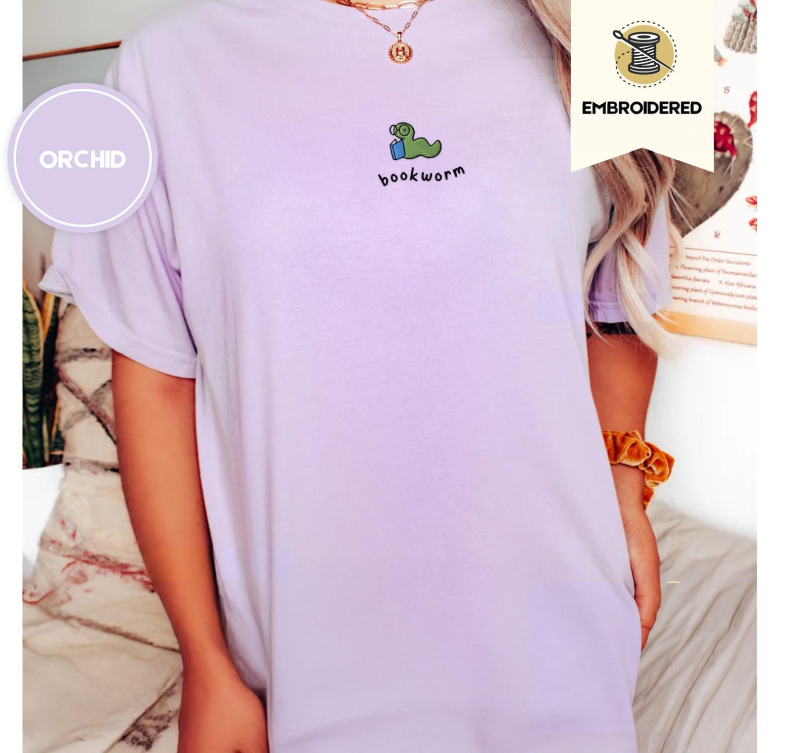 Person wearing an orchid Green Bookworm With Blue Book Embroidered T-Shirt