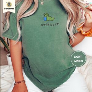 Person wearing a light green Green Worm Blue Book Embroidered T-Shirt