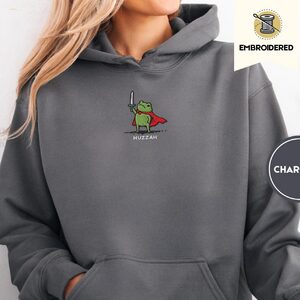Person wearing a charcoal Huzzah Knight Frog Embroidered Hoodie