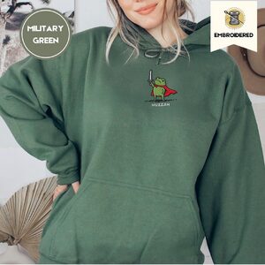 Person wearing a military green Huzzah Knight Frog Embroidered Hoodie
