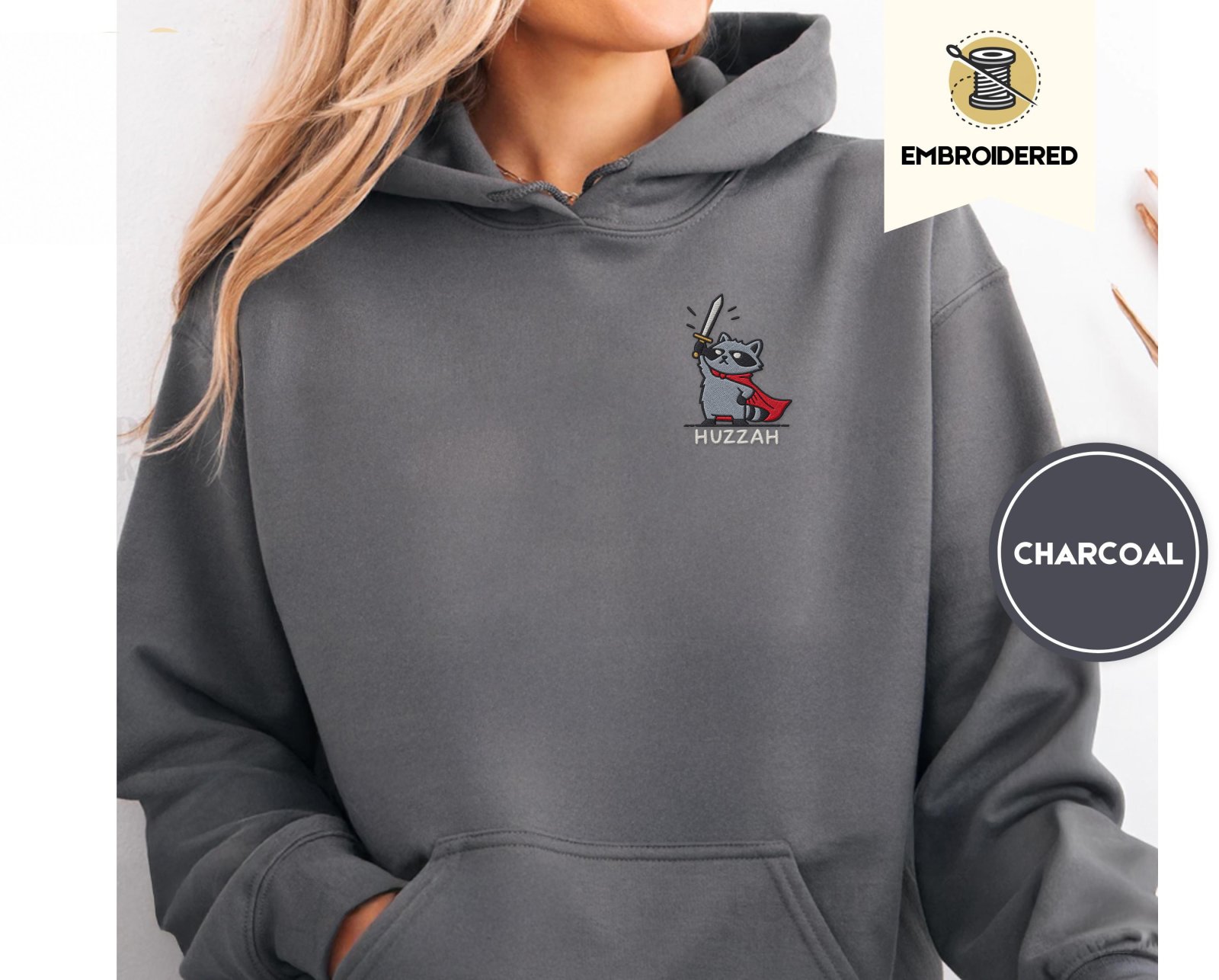 Person wearing a charcoal Huzzah Raccoon Knight Embroidered Hoodie