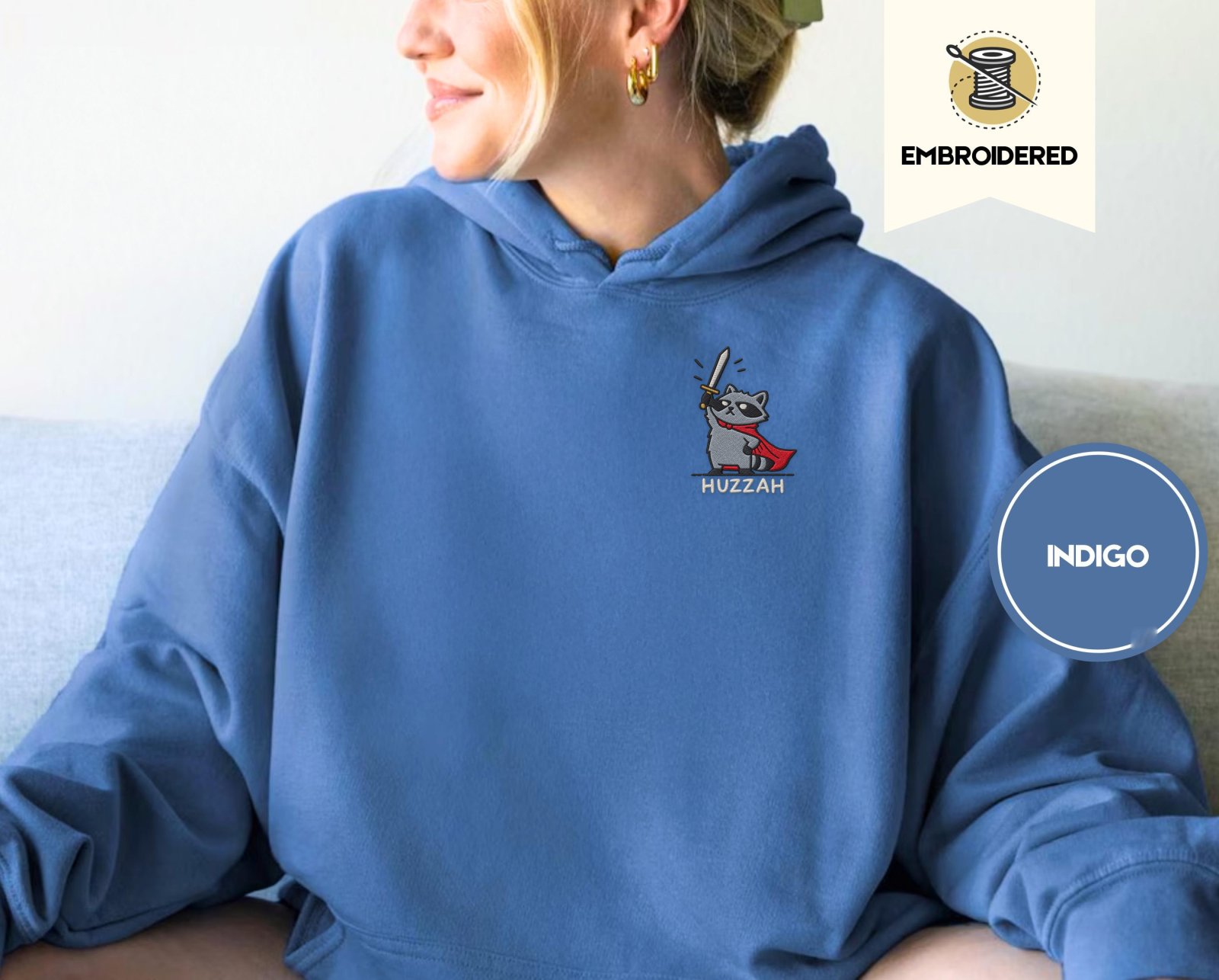 Person wearing an indigo blue Huzzah Raccoon Knight Embroidered Hoodie