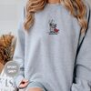 Person wearing a sport grey Huzzah Raccoon Knight Embroidered Sweatshirt