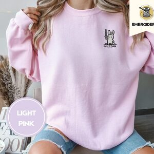 Person wearing a light pink Huzzah Sword Bunny Embroidered Sweatshirt