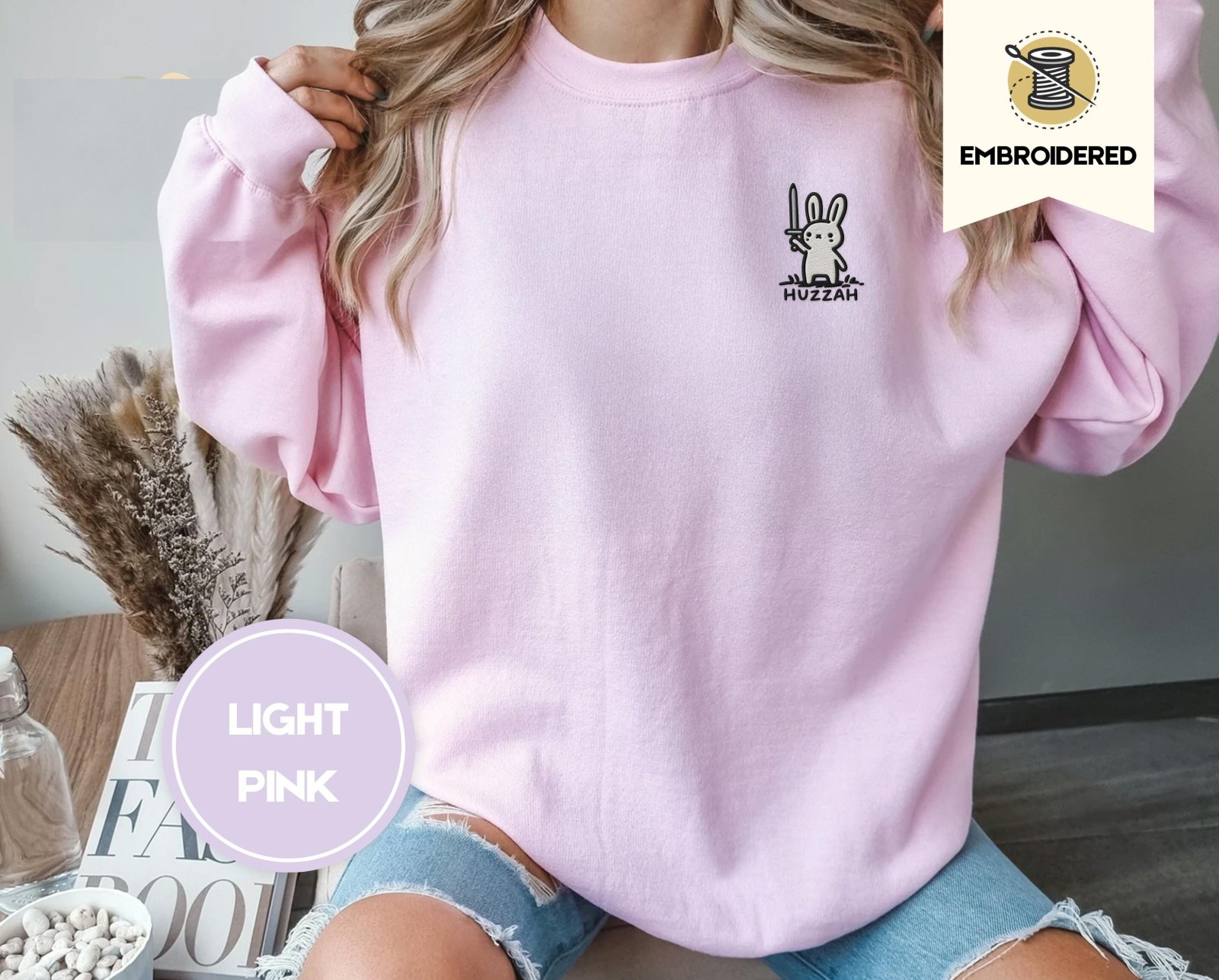 Person wearing a light pink Huzzah Sword Bunny Embroidered Sweatshirt
