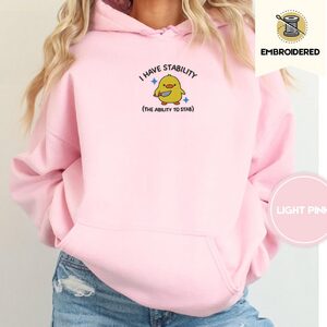 Person wearing a light pink I Have Stability Duck Embroidered Hoodie