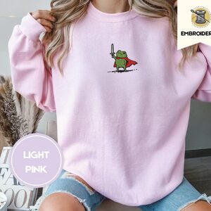 Person wearing a light pink Knight Frog Embroidered Sweatshirt