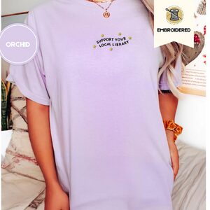 Person wearing an orchid Library Slogan and Yellow Stars Embroidered T-Shirt