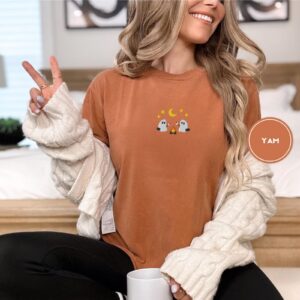 Person wearing a yam Marshmallow Roasting Ghosts Embroidered T-Shirt