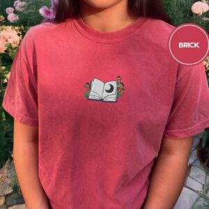 Person wearing a brick Moon and Mushroom Book Embroidered T-Shirt